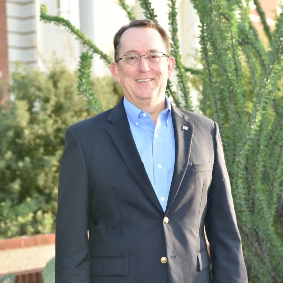 Dr. Louis Harveson standing outdoors in front of an ocotillo plant.