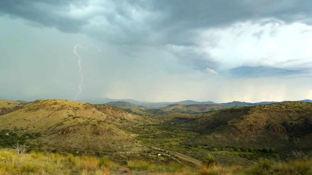Fort Davis Mountains with the town of Marfa in the background, under stormy skies with a bolt of lightning.