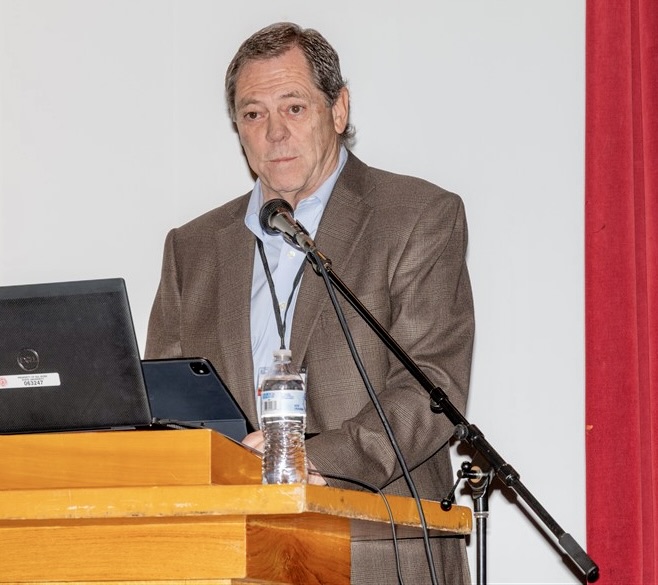 Paul Foster speaking at the conference podium.