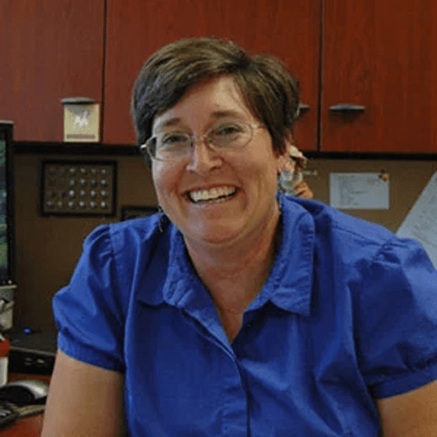 Bonnie Warnock smiling and seated at a desk indoors.