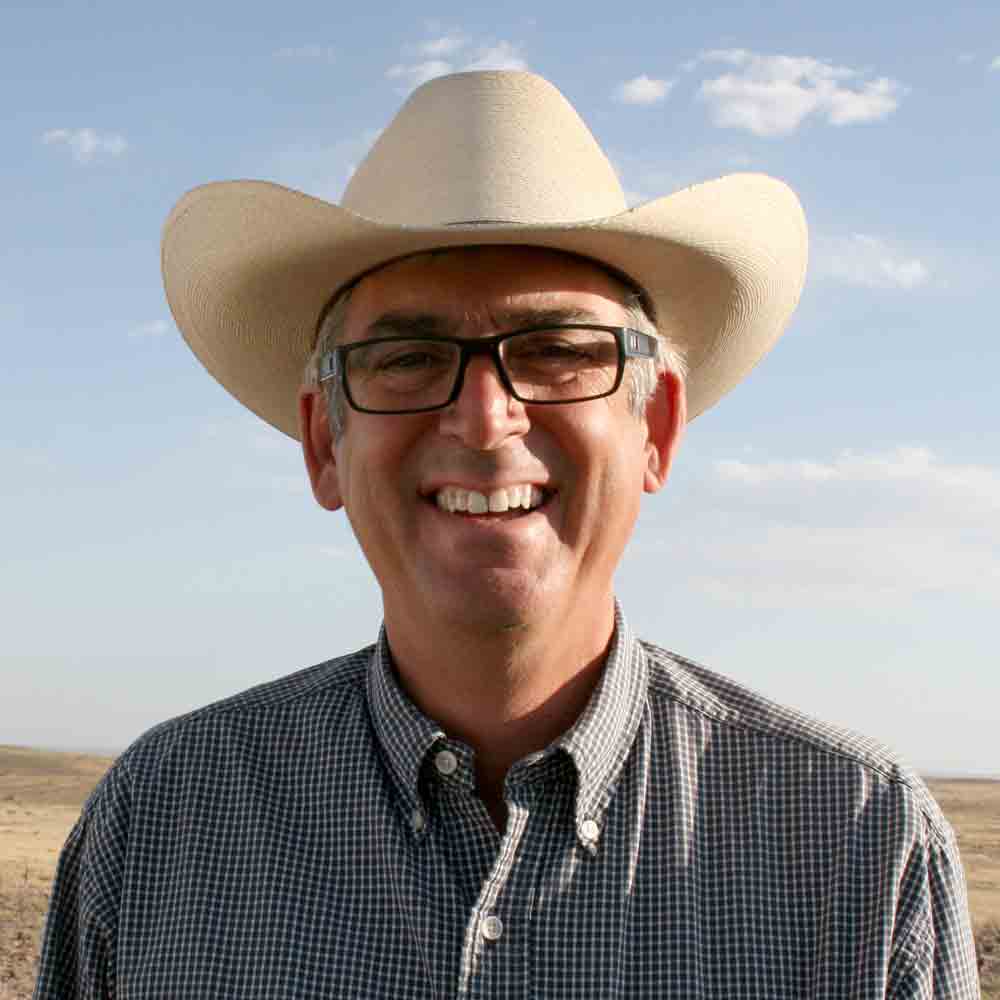 Robert J. Potts smiling with a western hat standing outdoors.